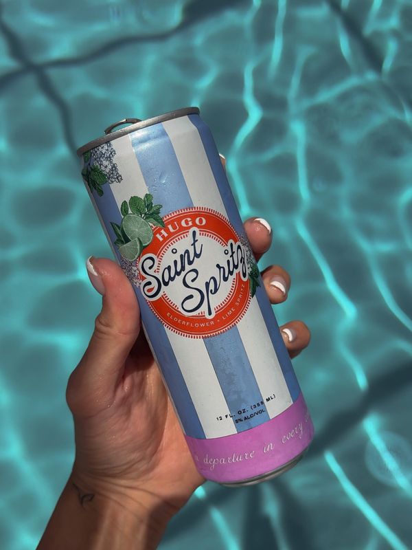 Hugo Saint Spritz held beside turquoise water
